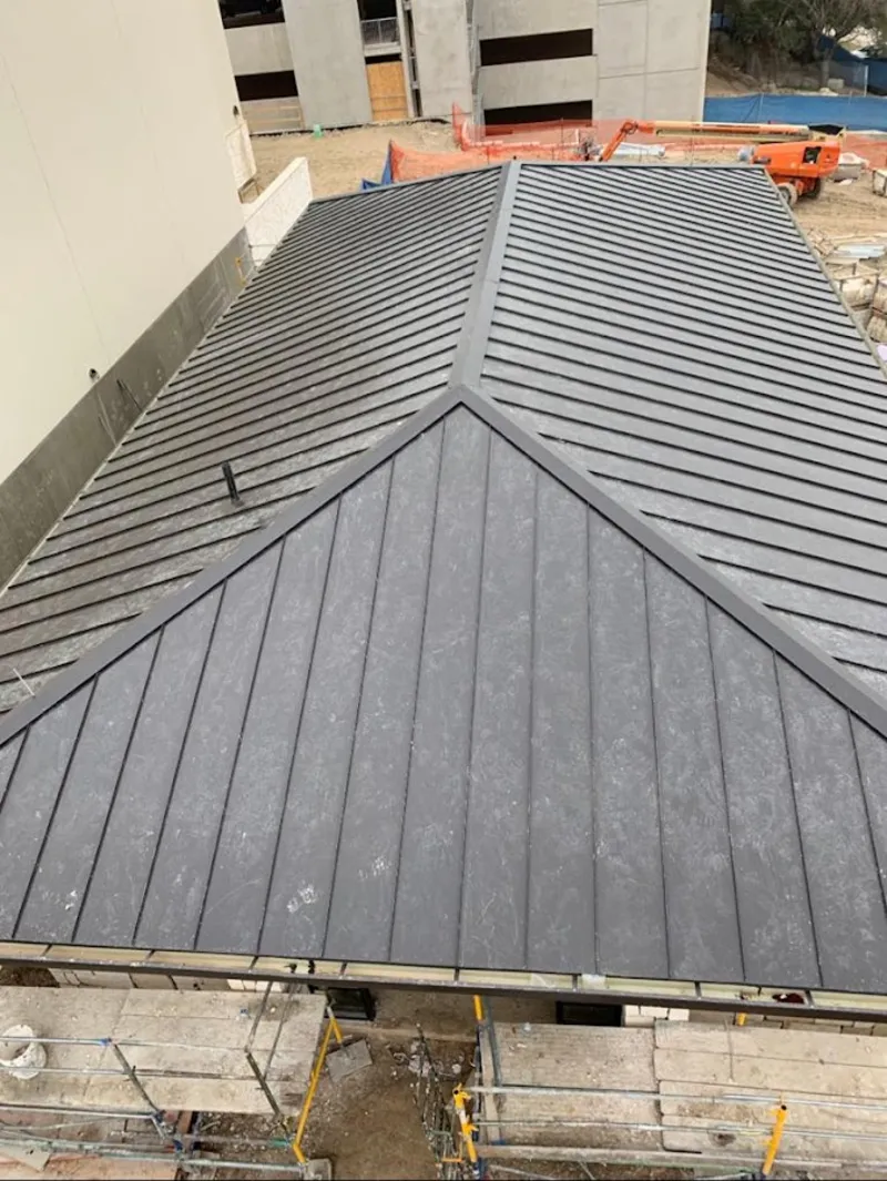 Commercial metal roof construction with crane equipment in Fate